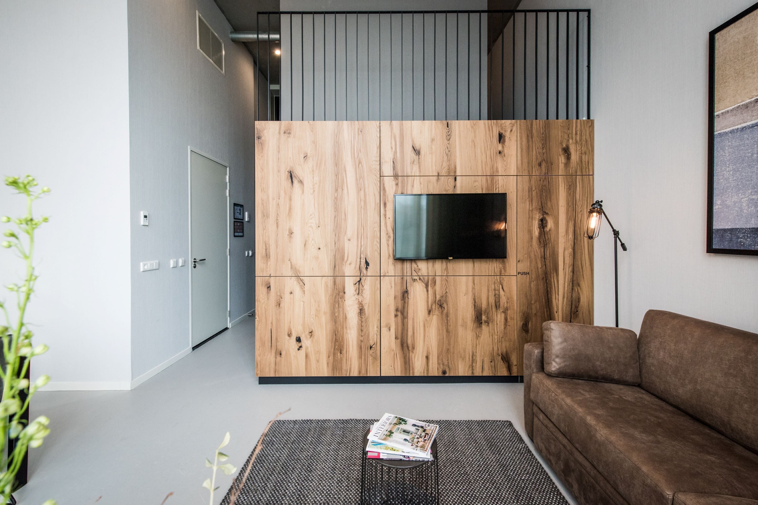 Una sala de estar moderna con una pared decorativa de madera, un televisor de pantalla plana, un sofá marrón y una revista sobre una mesita.