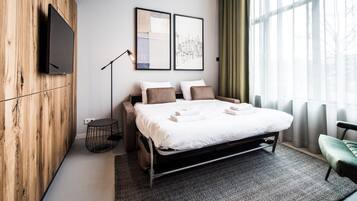 A modern hotel room with a bed, two pillows, a bedside table, a lamp, and a view of a cityscape through the window.