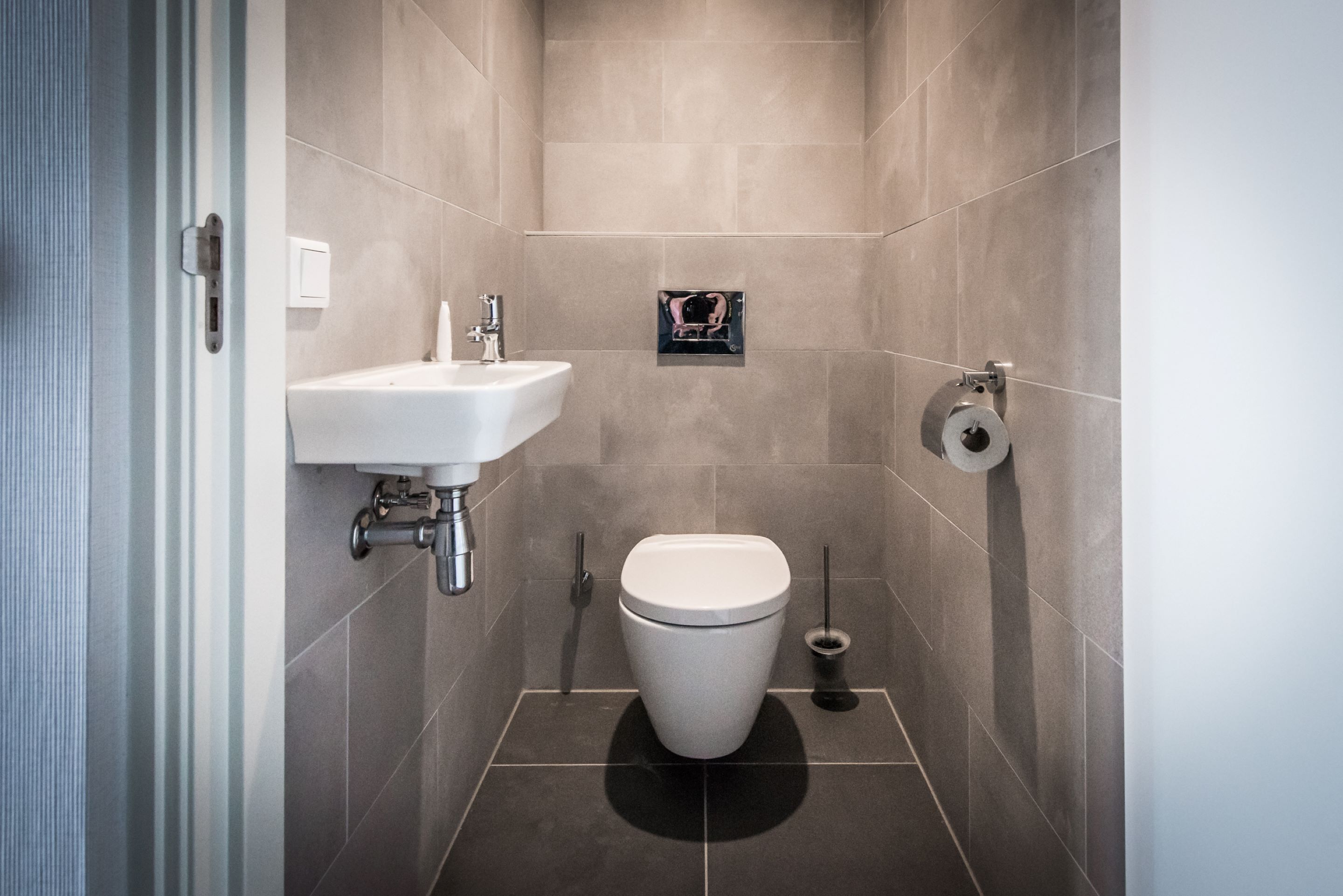 A modern bathroom with a white sink, toilet, and bidet.