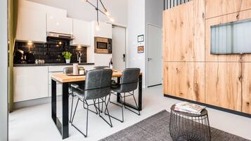 Una cocina moderna con armarios blancos, una mesa de comedor de madera y sillas negras.