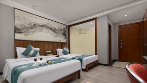 A hotel room with two beds, a large abstract painting on the wall, a wooden door, and a red chair. - Kaiserdom Hotel Airport Branch (Guangzhou)