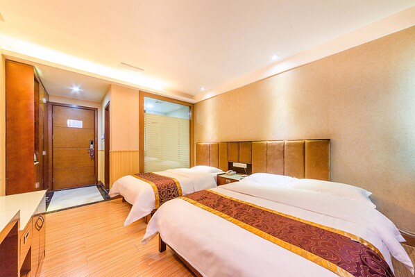 A hotel room with two beds, a wooden floor, a large mirror, and a door leading to a balcony.