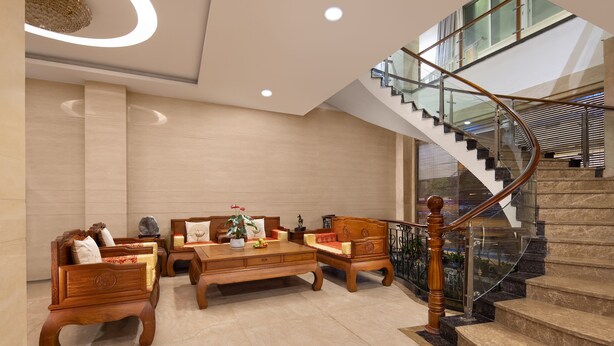 A spacious lobby with a wooden coffee table, sofas, and a staircase with glass railings. - Kaiserdom Hotel Airport Branch (Guangzhou)