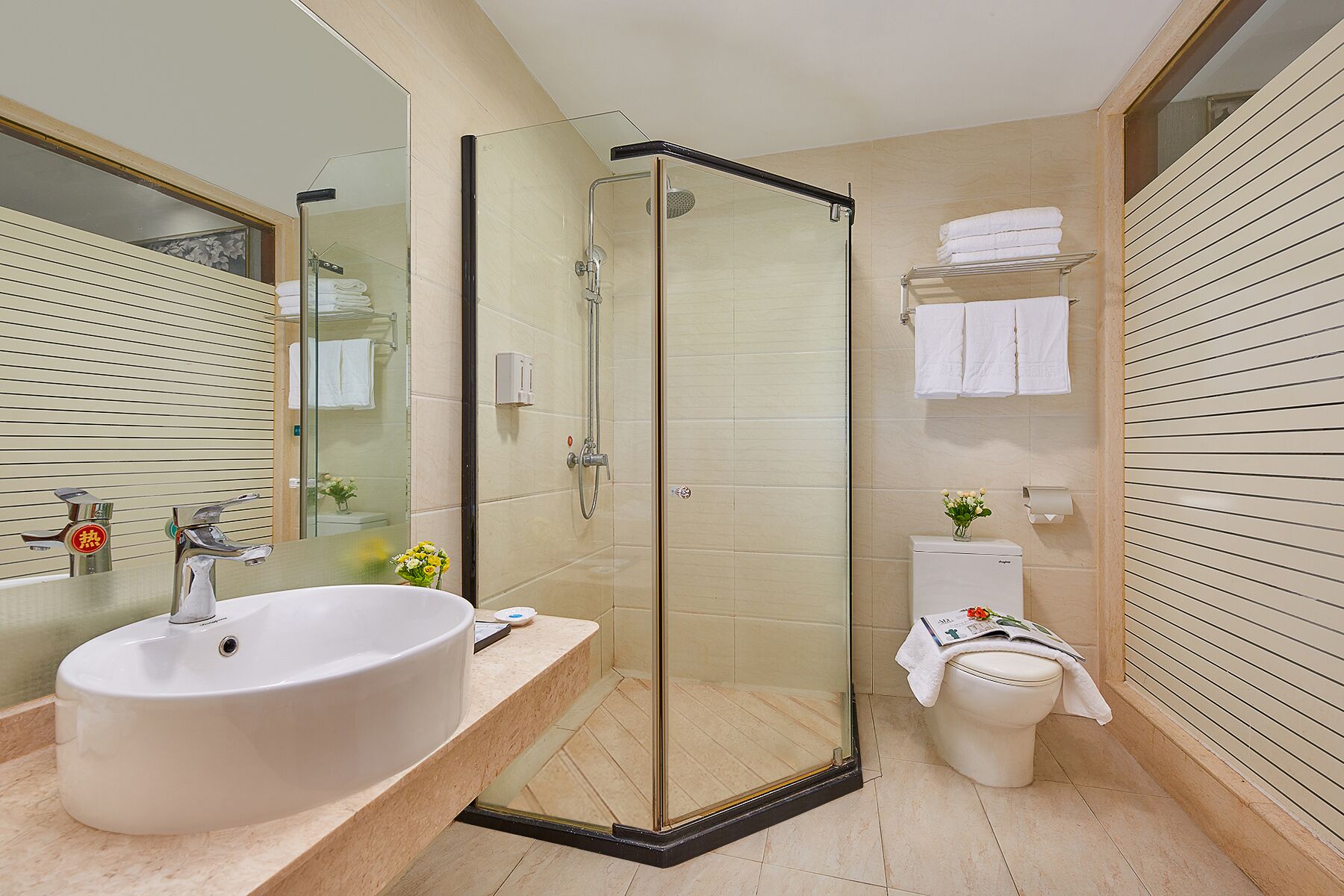 Een moderne badkamer met een douchecabine van glas, een groot wastafelmeubel en een toilet.