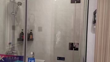 A modern bathroom with a glass-enclosed shower, a visible towel rack with a towel, and a sink area.