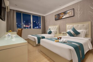 A hotel room with two beds, a desk, and a view of the city at night. - Kaiserdom Hotel Airport Branch (Guangzhou)