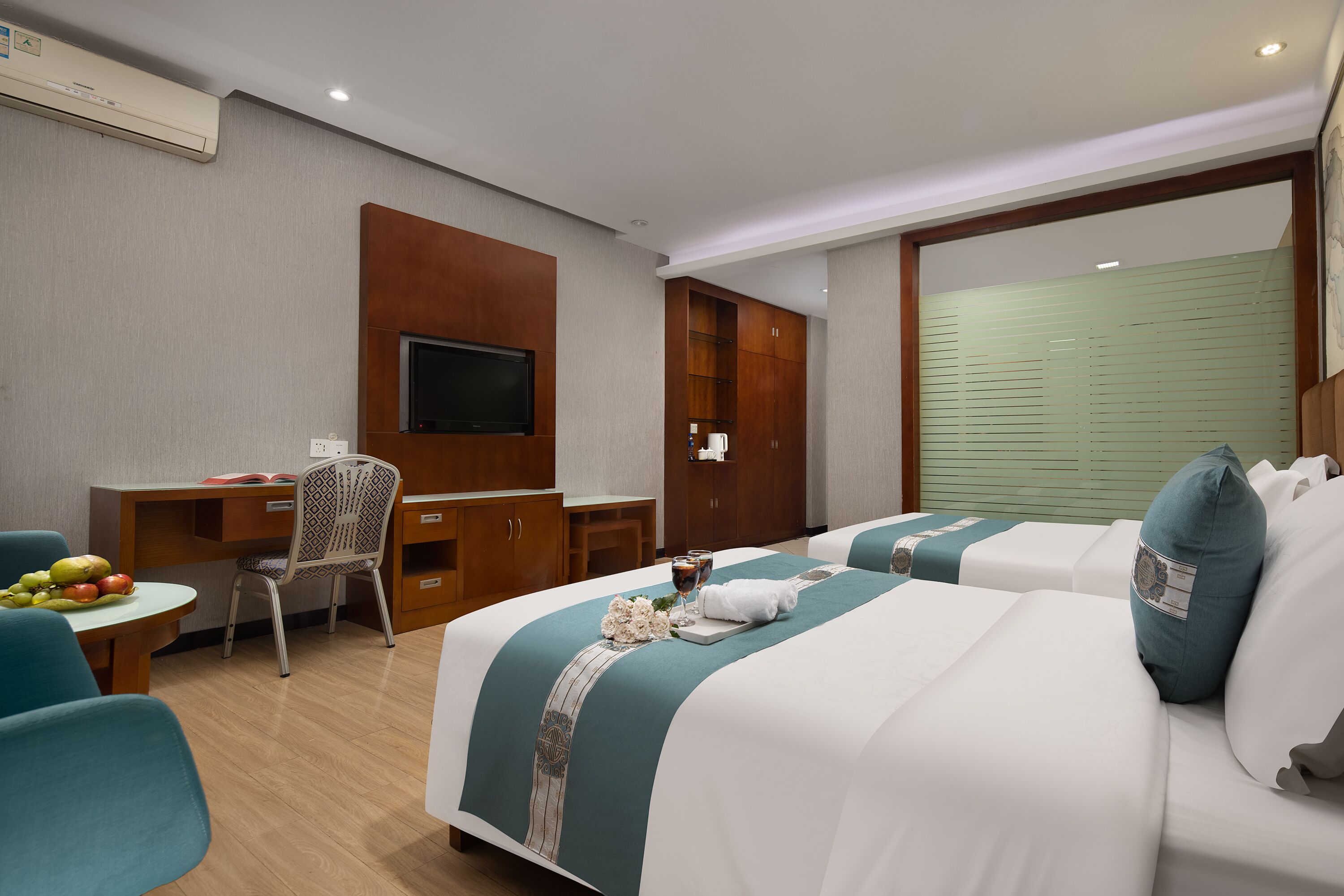 A hotel room with a bed, a desk, a chair, a TV, and a wardrobe.