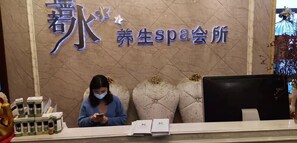 A reception desk with a sign reading "Youth Spa Salon" and a woman seated behind it. - Kaiserdom Hotel Airport Branch (Guangzhou)