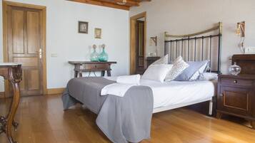 A bedroom with a wooden bed, a nightstand, a dresser, and a small table with decorative vases.
