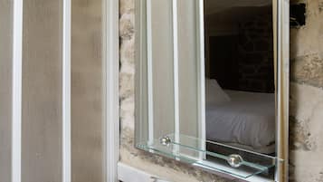 Een badkamer met een witte wastafel, een glazen plank, een spiegel en een handdoekhouder.