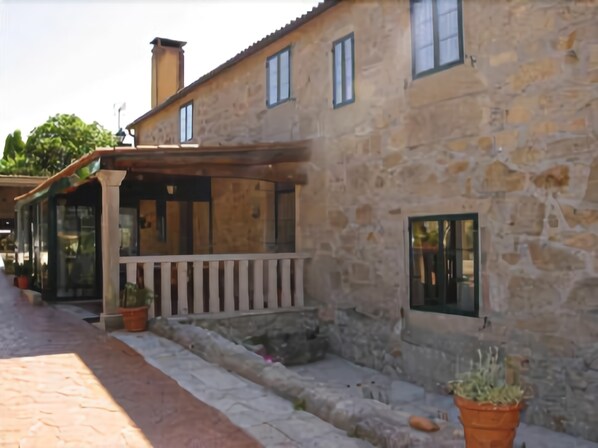 A stone building with a balcony, potted plants, and a clear sky.