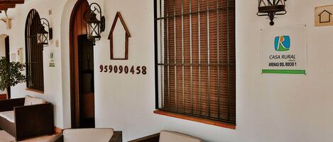 Una habitación de estilo rústico con muebles de mimbre, una puerta de madera y una ventana con persianas.