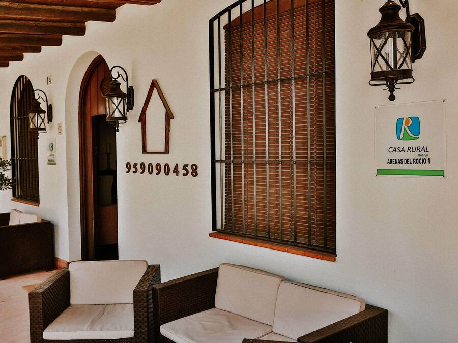 A rustic-style room with wicker furniture, a wooden door, and a window with blinds.