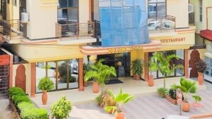 Un hôtel à plusieurs étages avec un restaurant situé au rez-de-chaussée, doté de balcons et agrémenté de plantes en pot.