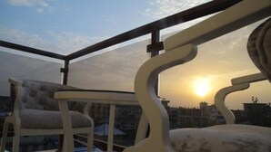Un balcon offrant une vue sur le coucher de soleil, avec deux chaises et une table.