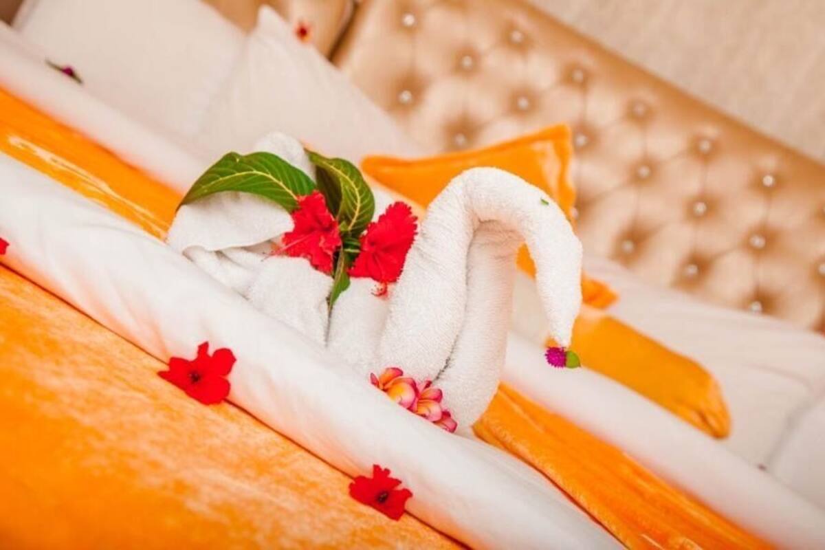 Un lit avec une serviette blanche ornée d’un motif de cygne et des fleurs rouges.
