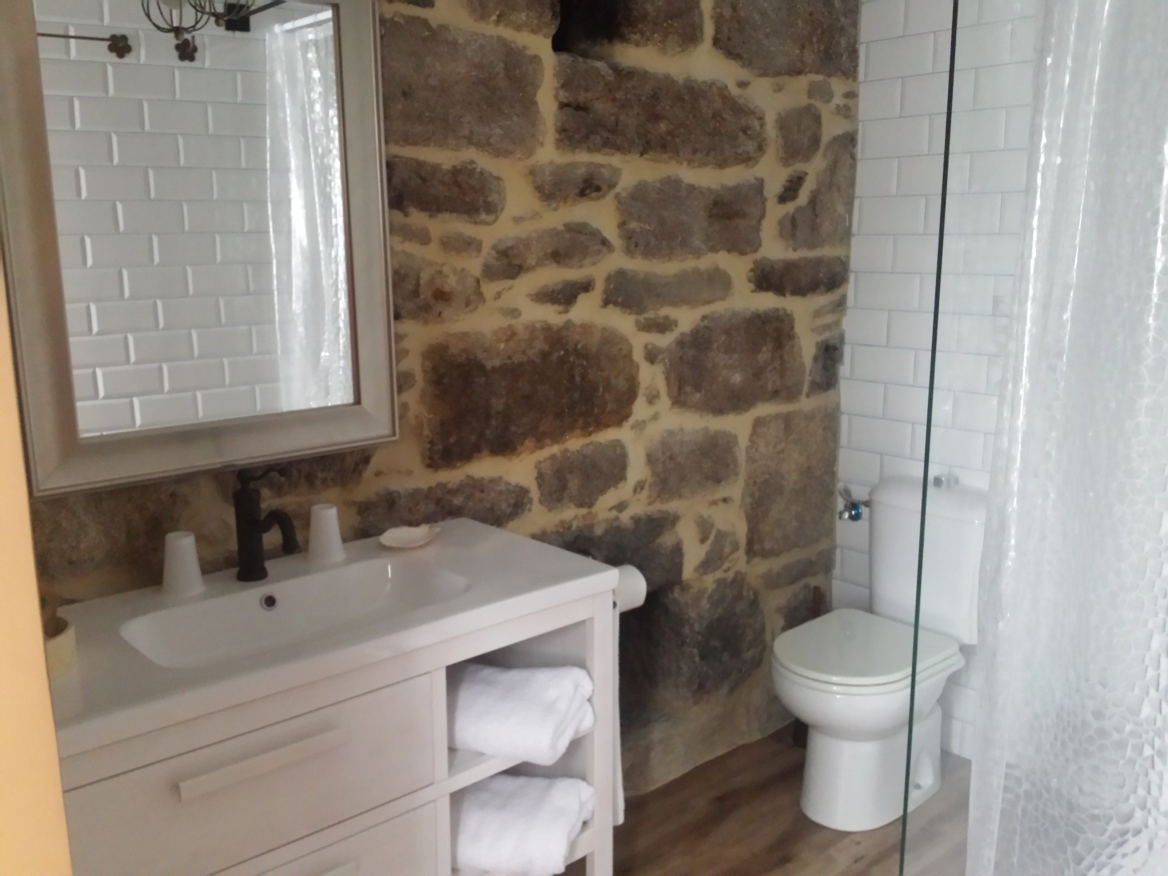 A bathroom with a stone wall, a white sink, and a toilet.