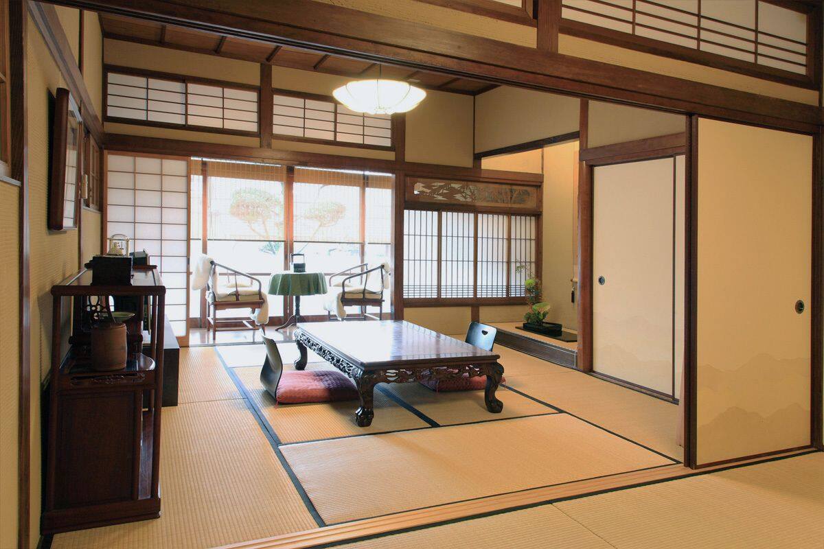 Une pièce de style japonais traditionnel, avec un sol recouvert de tatamis, une table basse et des portes coulissantes.