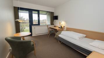Quarto de hotel com cama, escrivaninha, cadeira, mesa e televisão.