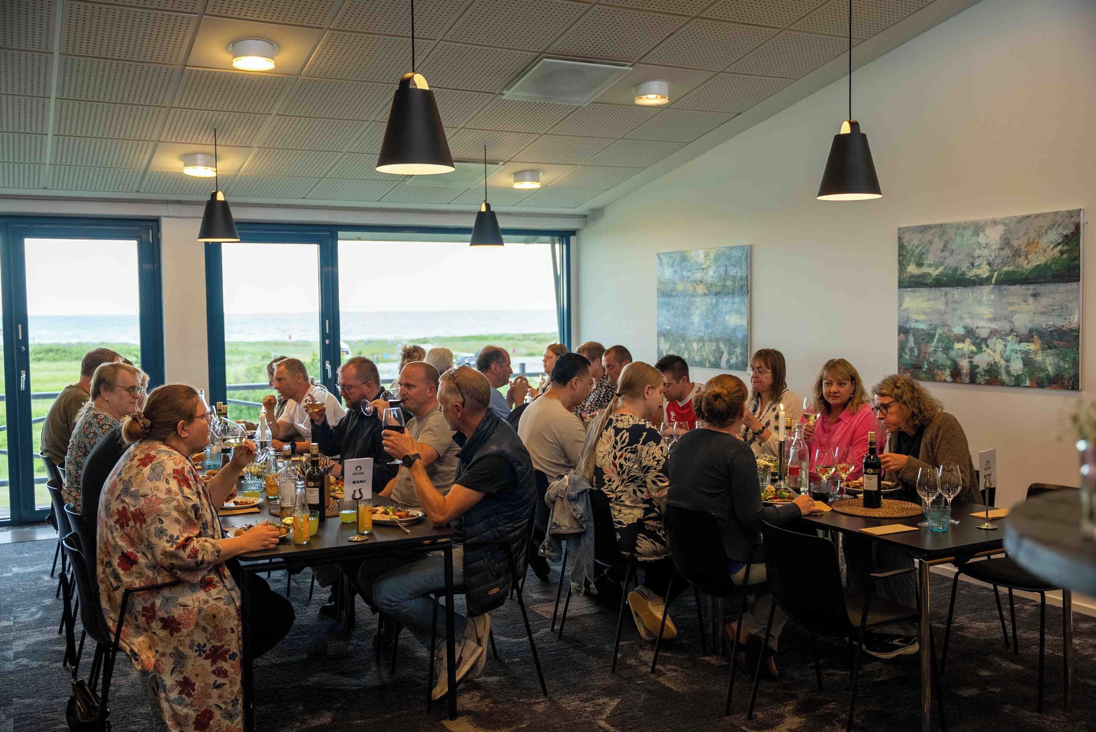 A group of people dining at a table with a view of the outdoors.