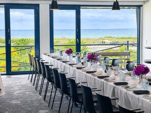 Un comedor con una mesa dispuesta para seis personas, ventanas amplias y vista al océano.