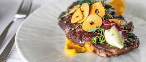 A plate with a steak, vegetables, and a sauce.
