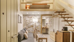 Um espaço compacto com quarto em mezzanine, sofá, mesa e cozinha.