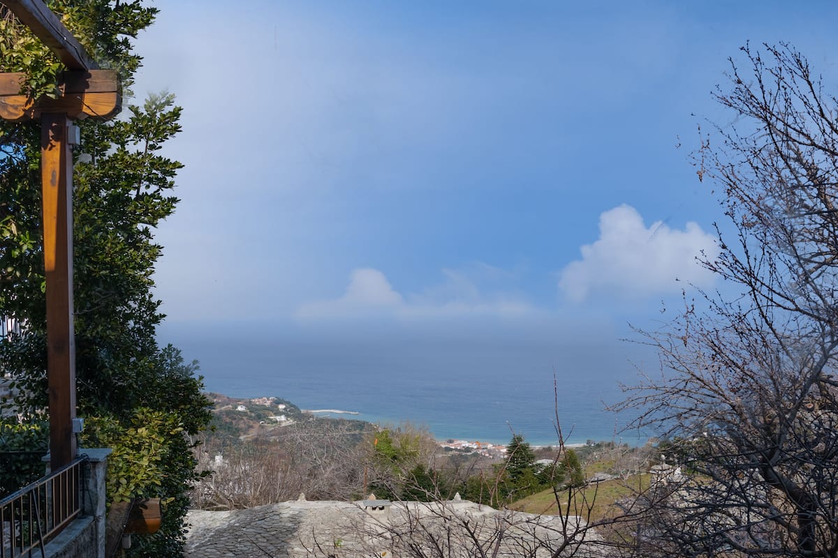Vista costera con un sendero de piedra que lleva a un edificio con balcón con vista al mar.