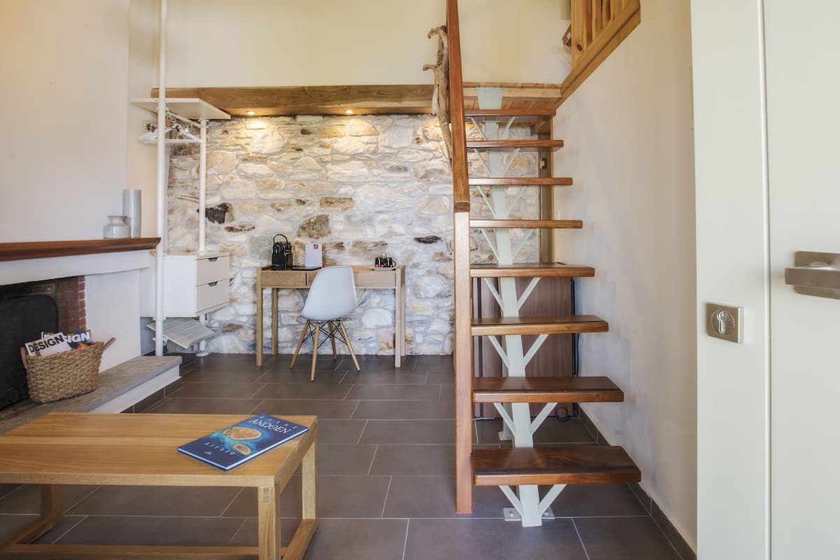 Un interior acogedor con una escalera de madera, una pared de piedra, una chimenea y un comedor.