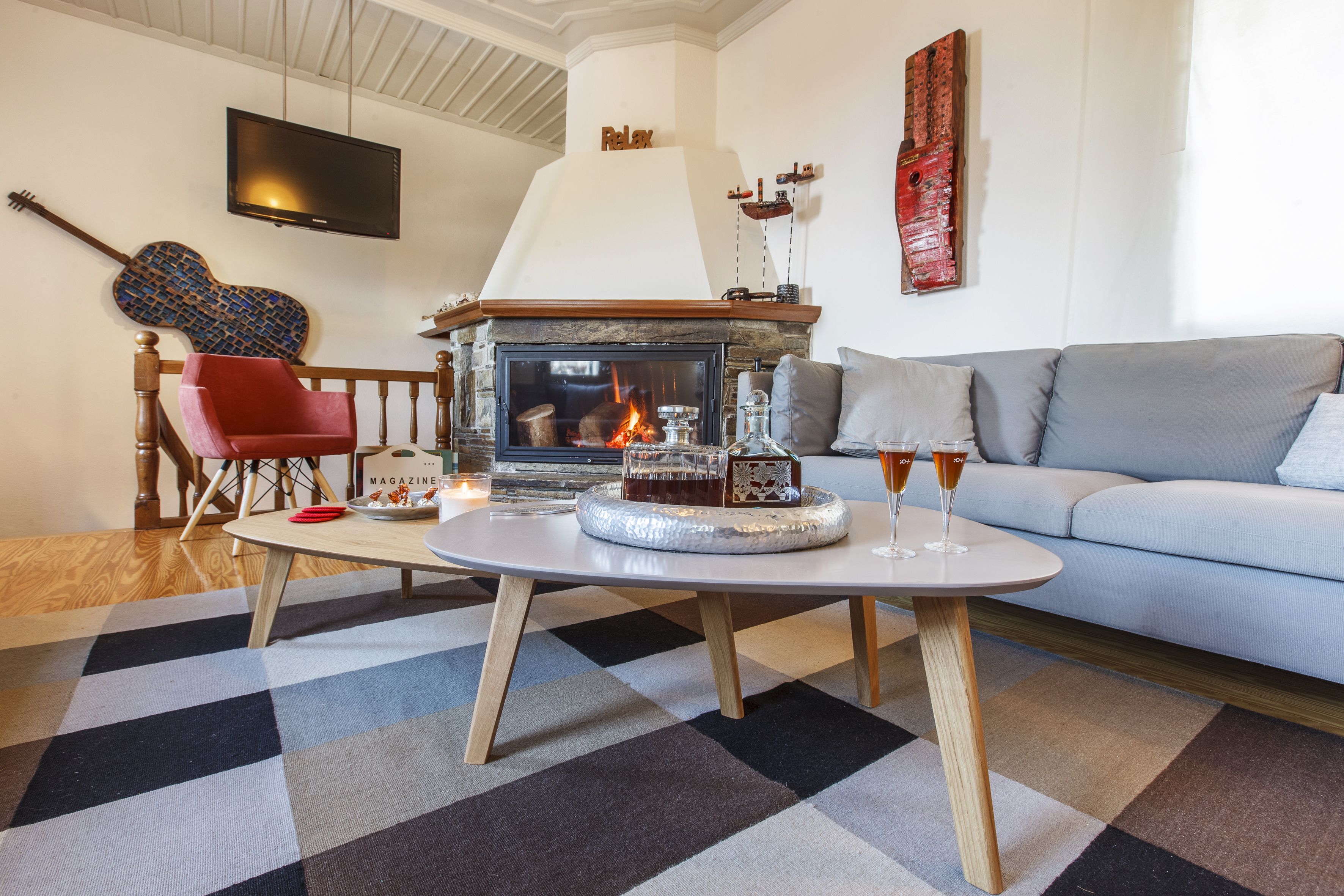 Una sala de estar acogedora con chimenea, un sofá, una mesita de centro y una butaca roja.