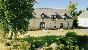 A stone building with a symmetrical facade, a central entrance, and a well-maintained lawn with outdoor seating. - Domaine De Kerstinec (Riec-sur-Belon)