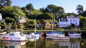 A marina with several boats docked, surrounded by lush greenery and white buildings. - Domaine De Kerstinec (Riec-sur-Belon)