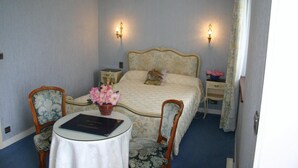 A bedroom with a bed, two nightstands, a table with a book, two chairs, and a vase of flowers. - Domaine De Kerstinec (Riec-sur-Belon)