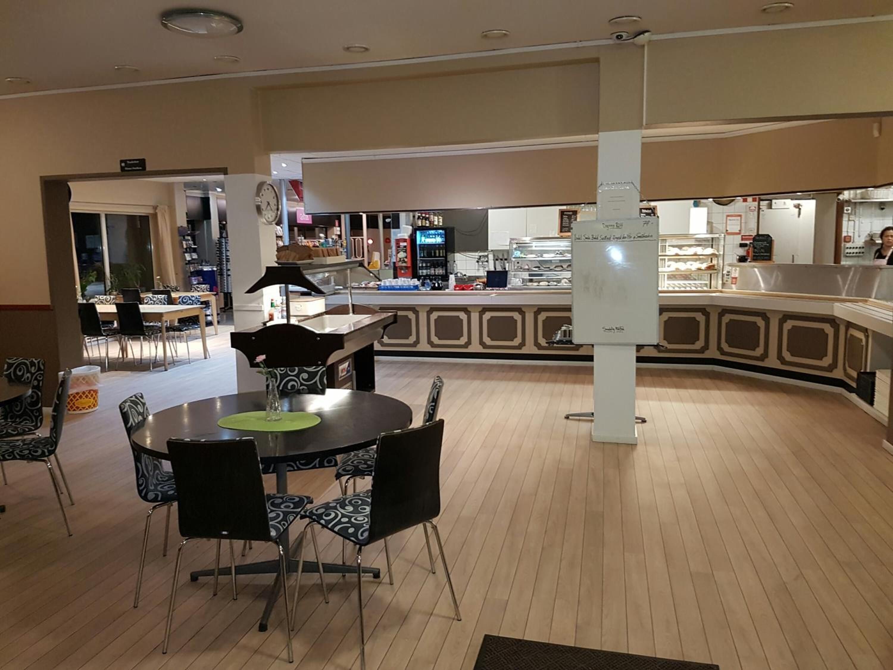 Un restaurante con una barra curva, sillas negras con cojines estampados y un reloj en la pared.