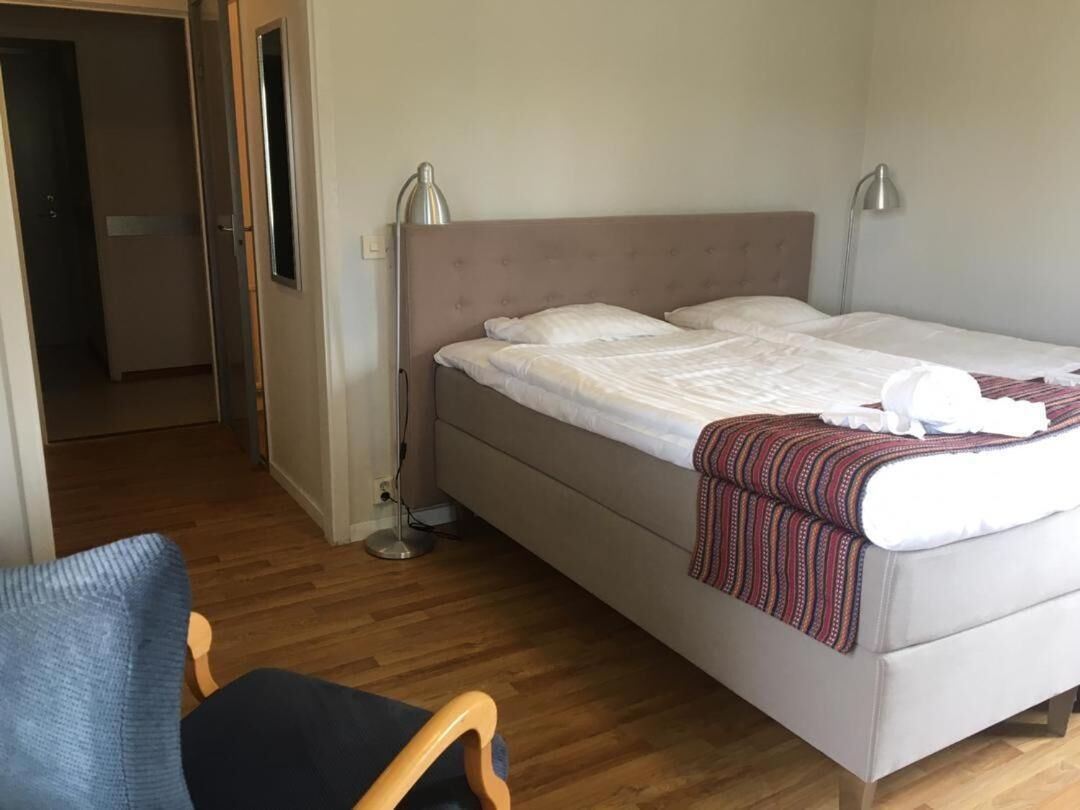 A single bed with a headboard, a bedside lamp, and a blanket.