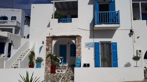 A white building with blue shutters and a stone staircase leading to a door. - Angelos Rooms (Naxos)