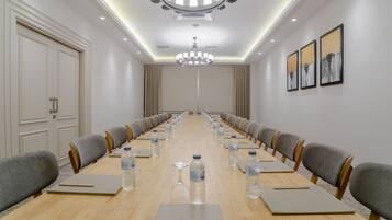 A conference room with a long table, chairs, water bottles, and a chandelier.