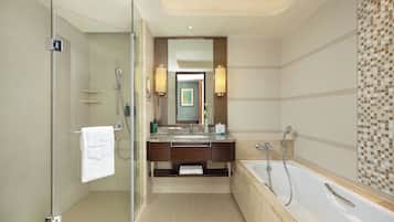 A modern bathroom with a glass shower enclosure, a bathtub, and a vanity with a mirror.