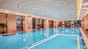 A large indoor swimming pool with a tiled floor and walls, surrounded by windows and doors. - Shangri-La Jinan (Jinan)