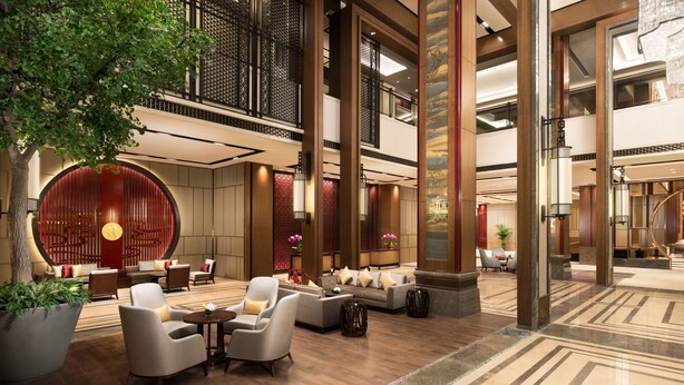 A spacious lobby with a large seating area, a decorative wall, and a staircase leading to an upper level. - Shangri-La Jinan (Jinan)