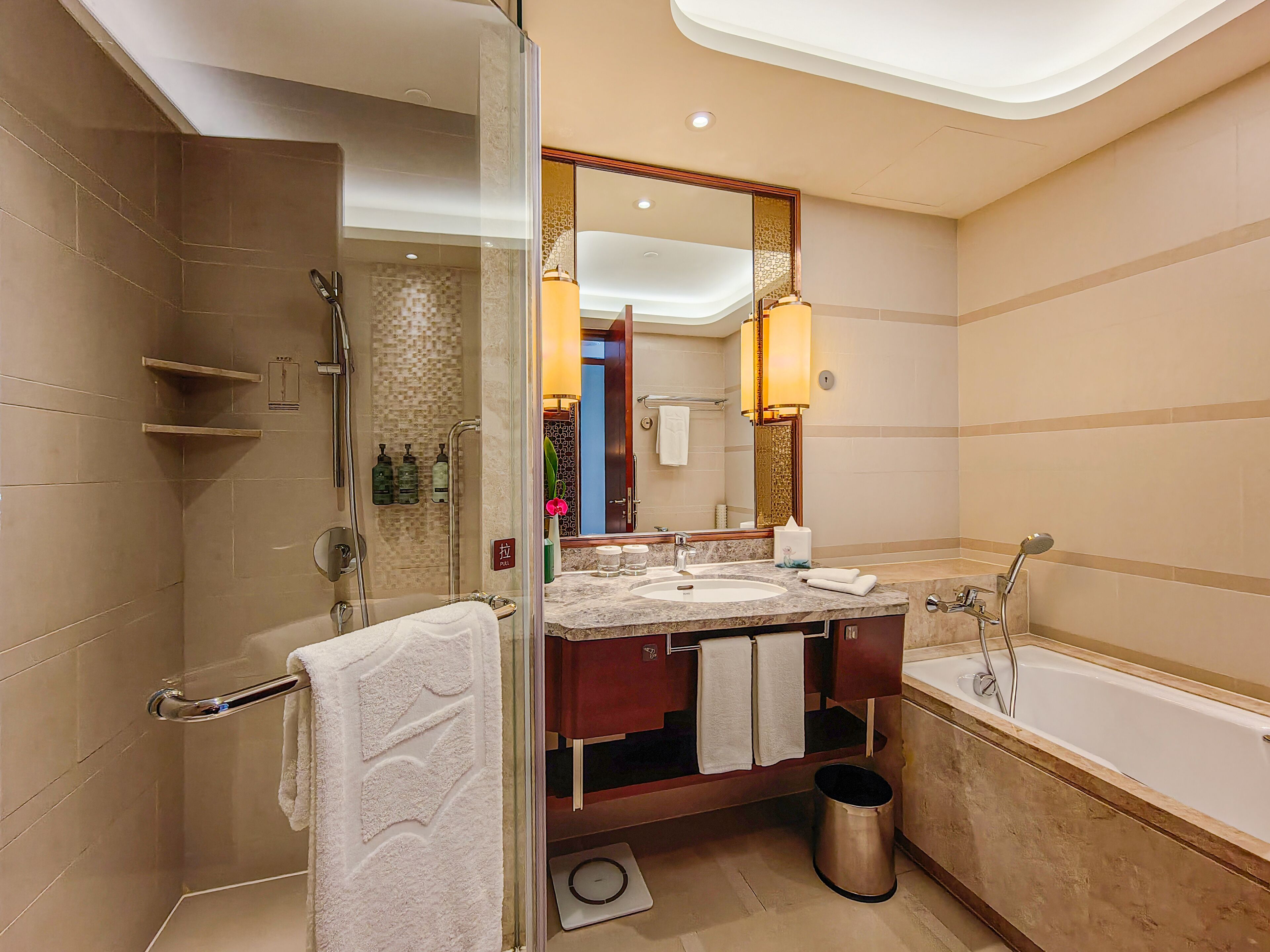 Un baño moderno con ducha a ras de suelo, bañera y tocador con un espejo grande.