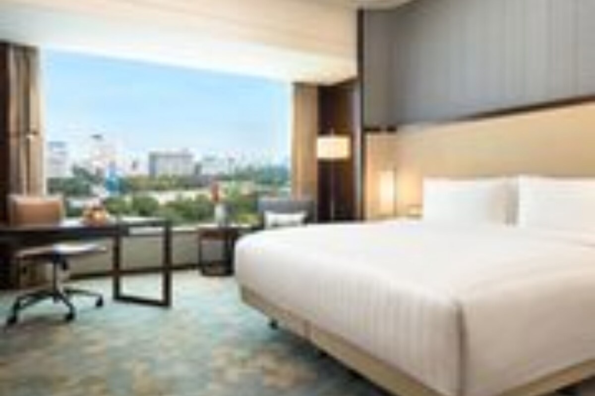 Habitación de hotel con una cama grande, un escritorio y vistas a la ciudad.