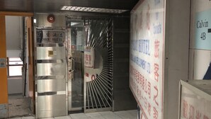 A hotel entrance with a metallic door, a push button, and a tiled floor. - Tohou Hotel (Kowloon)