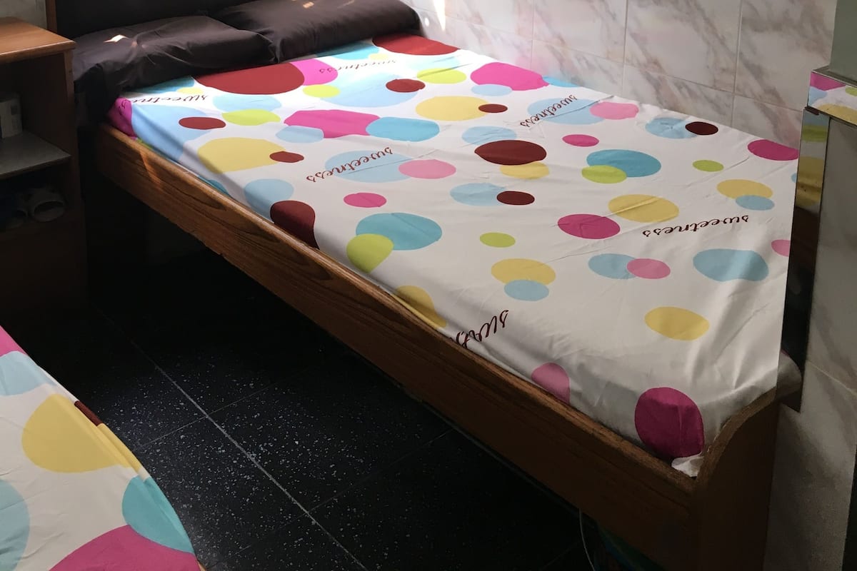 A small, neatly arranged bedroom with a bed, a chair, and a desk.