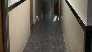 A corridor with tiled floors, fluorescent lighting, and informational posters on the walls. - Tohou Hotel (Kowloon)