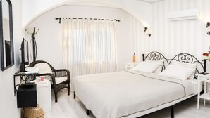 A bedroom with a large bed, a chair, a nightstand, a lamp, and a mirror. - A&B Home Hotel (Fethiye)
