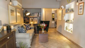 A living room with a sofa, a coffee table, a bookshelf, and a chair. - A&B Home Hotel (Fethiye)