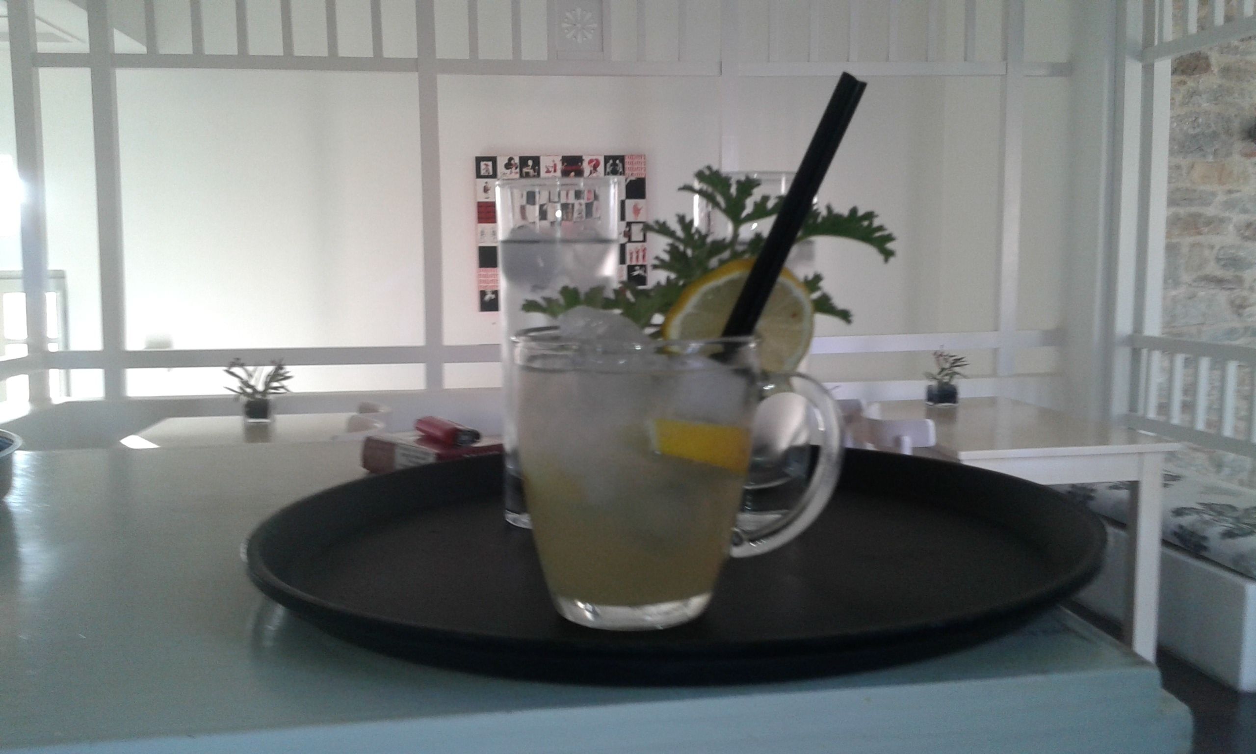A glass of iced tea with a lemon slice and a straw on a tray.