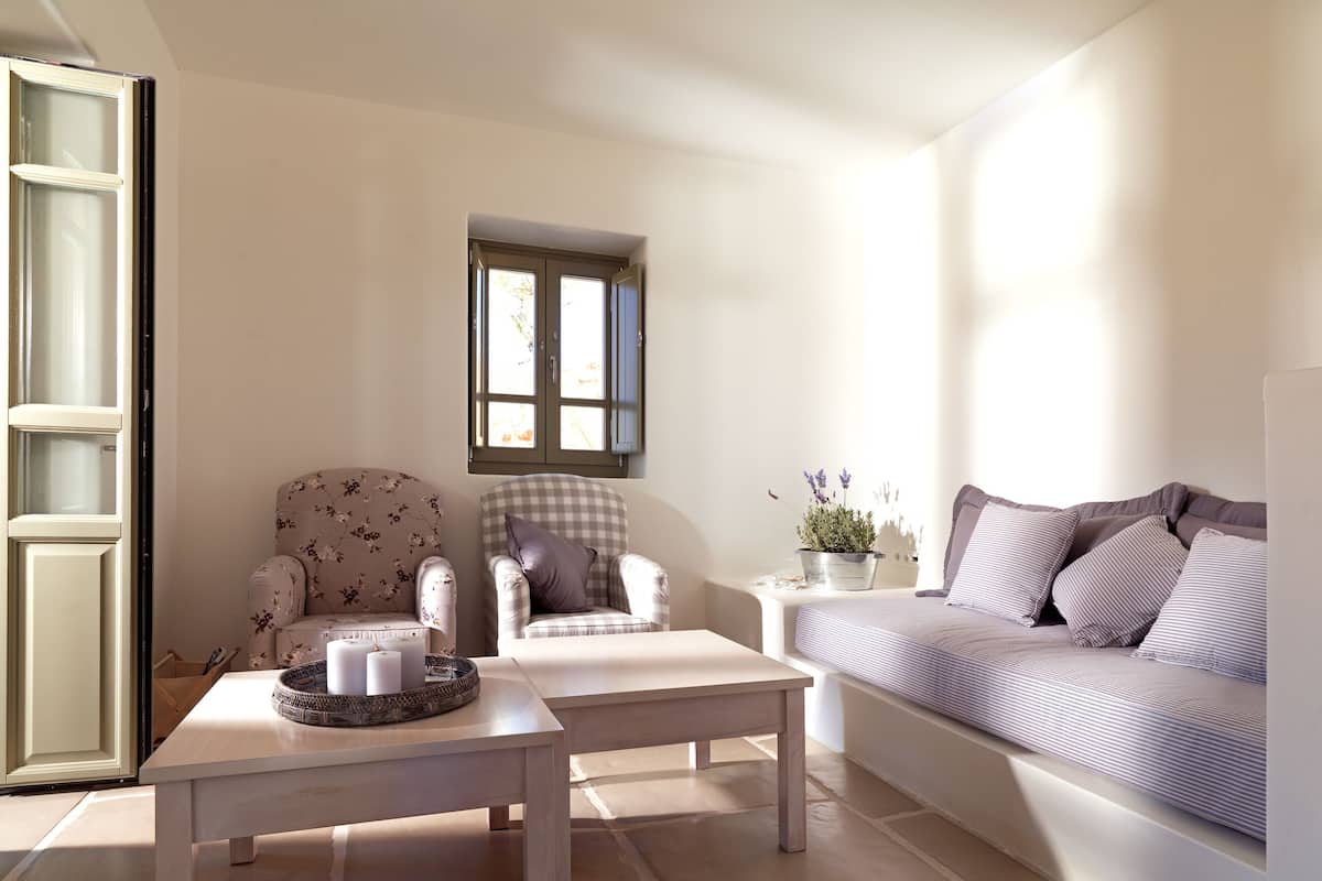A cozy living room with a sofa, two armchairs, a coffee table, and a small window.