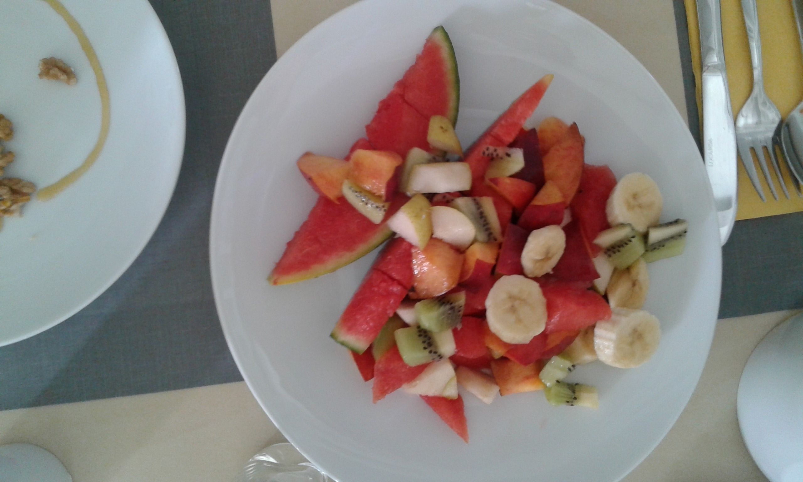 A plate of fruit salad with watermelon, kiwi, and banana pieces.